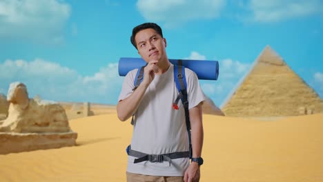 asian male hiker with mountaineering backpack thinking about something and looking around then raising his index finger while traveling in pyramid of giza