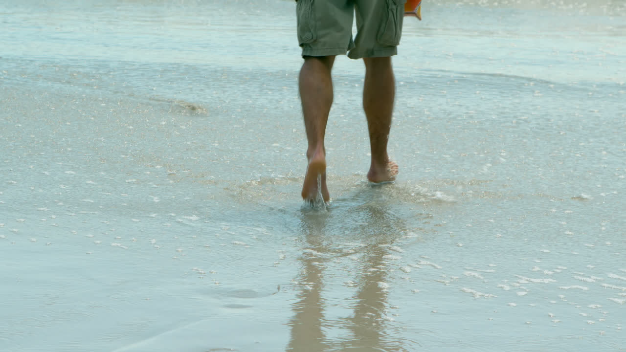 해변 4k에서 바다를 향해 달리는 남성 서퍼의 낮은 섹션