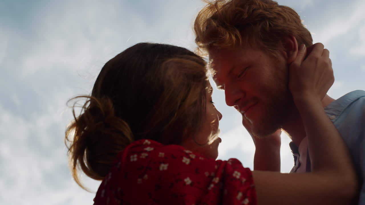 Closeup affectionate couple cuddle together outside. Lovers enjoy sun sky nature