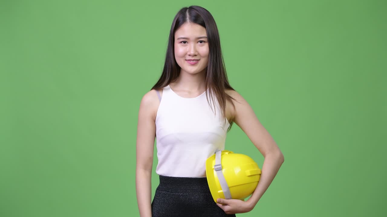 Young beautiful Asian businesswoman as engineer giving thumbs up