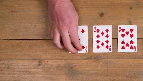 a person laying out a flush draw diamonds on a wooden table to educate the viewer on how to play poker