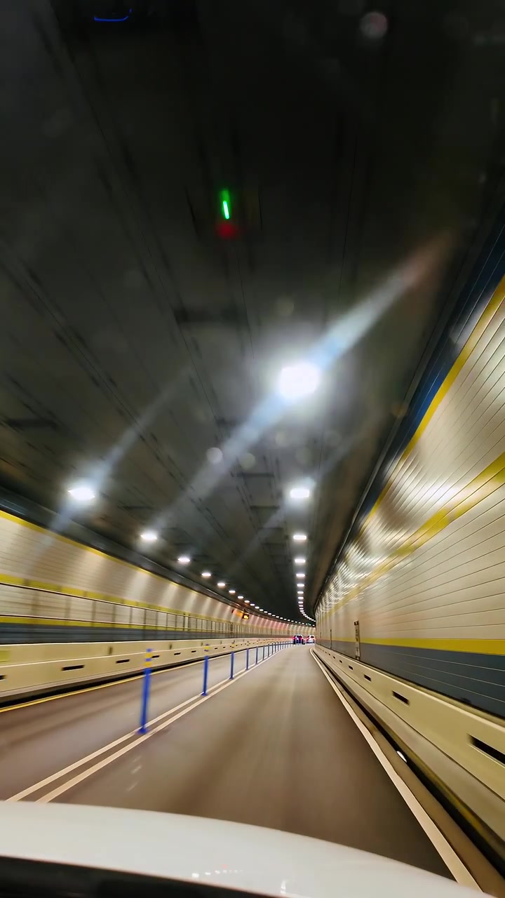 Prospettiva con sfocatura di movimento ad alta velocità all'interno di un tunnel stradale vuoto. Vista di guida ad alta velocità attraverso un tunnel stradale illuminato con pareti bianche e motivi luminosi sul soffitto