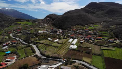 village on beautiful hills, greenhouses, agricultural parcels and mountains background in albania