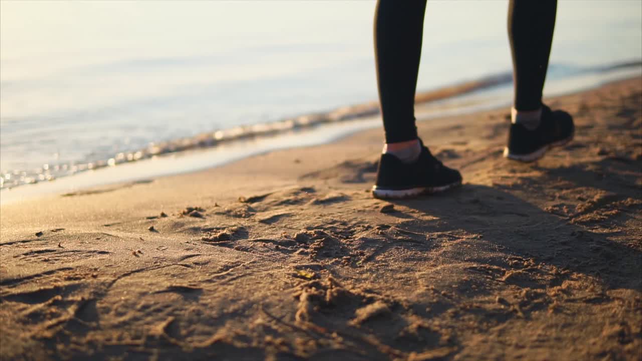 mujer caminando por la playa al atardecer