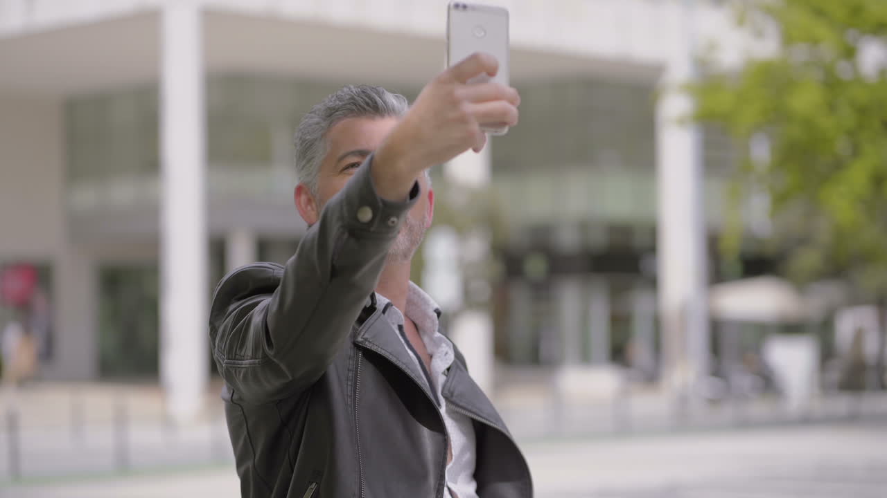 Mature man taking selfie with smartphone on street