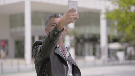 mature man taking selfie with smartphone on street