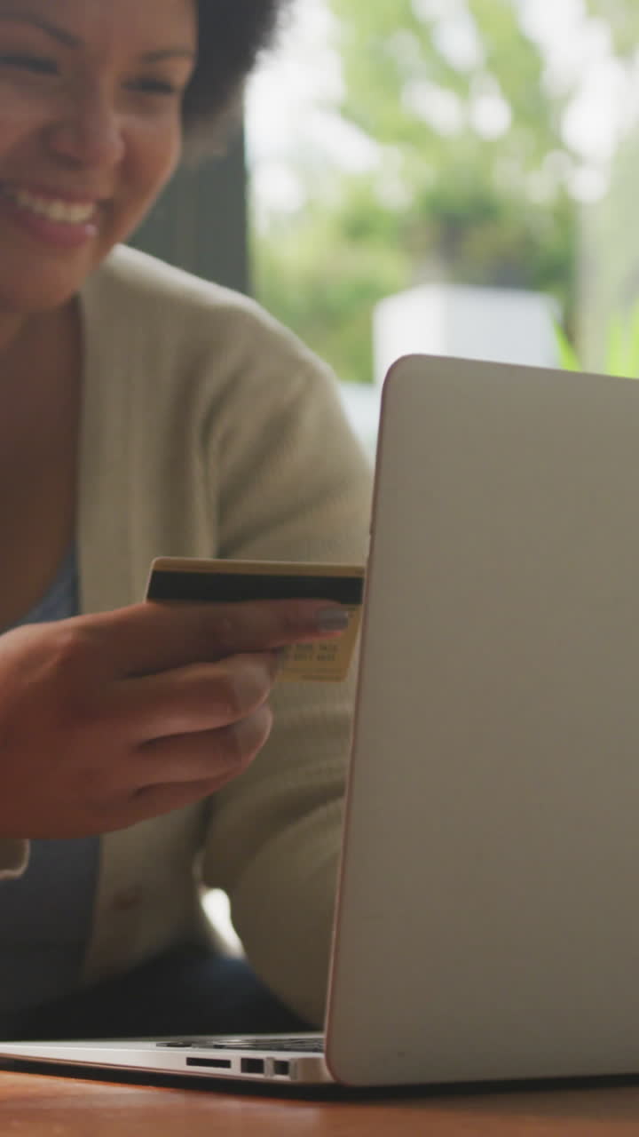 video de una feliz mujer afroamericana de tamaño plus con tarjeta de crédito y usando una computadora portátil