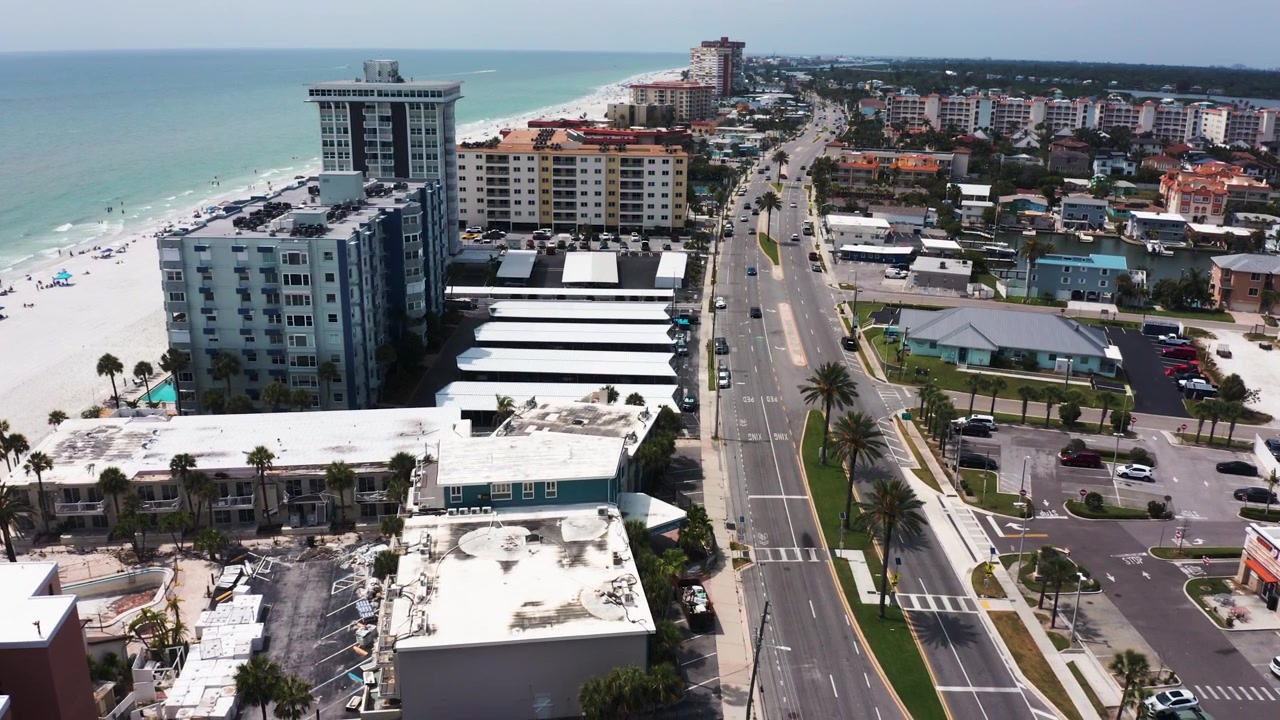 Imagens aéreas capturam uma estrada costeira ladeada por apartamentos altos e uma orla movimentada. Perfeito para planejamento urbano ou marketing imobiliário