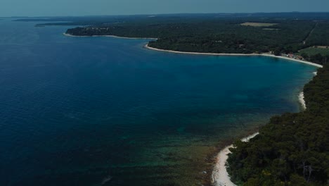 Filmische-Luftbilddrohne-über-Einer-Blauen,-Klaren-Wasserküstenfelsenstrandbucht-Im-Idyllischen-Adriatischen-Mittelmeerozean-Im-Sommer-An-Der-Kroatischen-Küste-Mit-Blauem-Himmel-In-Der-Nähe-Von-Pula-Und-Rovinj