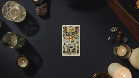 overhead shot of person giving tarot card reading laying down the judgement card on table