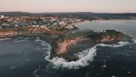 Sunrise-Drone-shot-at-the-cliffs-and-coastline-of-The-Skillion-in-Terrigal,-NSW,-Australia