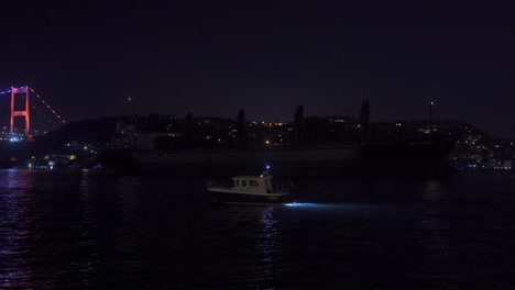 dark giant ship passing through the bosphorus at night.