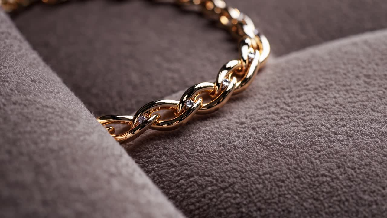 Close-up video angle of a gold chain on soft fabric, highlighting luxury and elegance with a focus