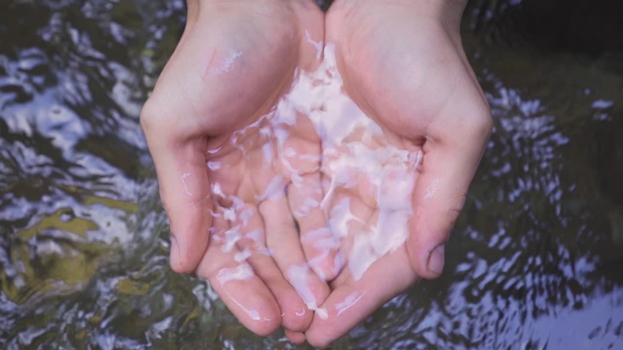 한 손이 하천에서 물을 잡습니다. 슬로우 모션.