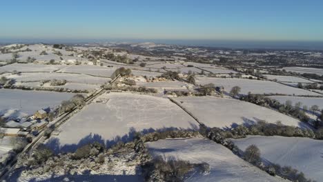 frío nevado invierno británico patchwork tierras de cultivo campo rural escena aéreo al amanecer lento cinemático pan derecho