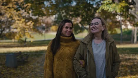 caucasian women walking together in park in autumn.