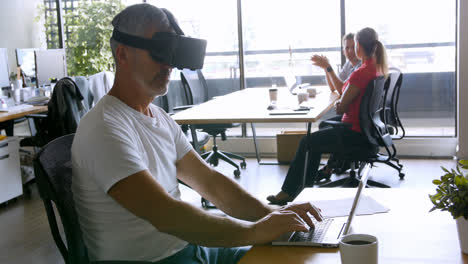 Männliche-Führungskraft-Mit-Virtual-Reality-Headset-Und-Laptop-Am-Schreibtisch-4K