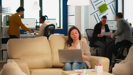 Manager-woman-sitting-on-couch-holding-laptop-and-talking-on-video-call