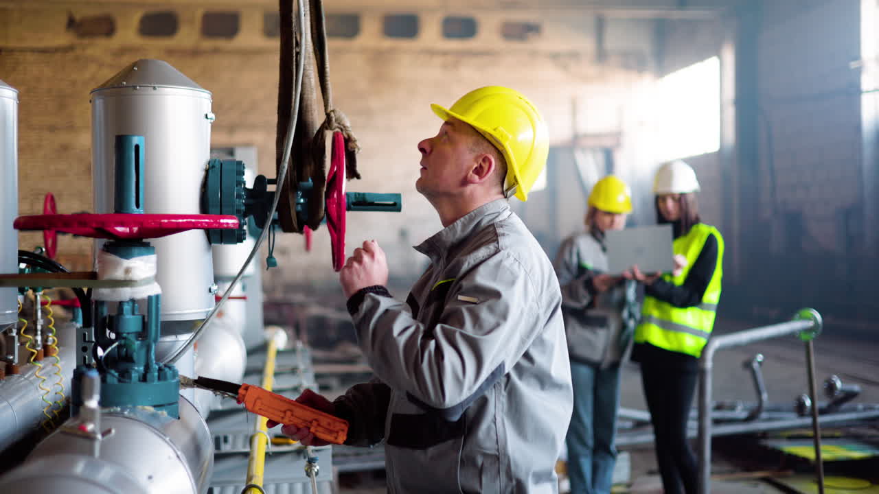 Man in yellow hardhat is checking the machinery