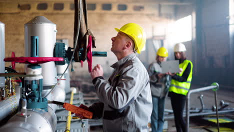 man in yellow hardhat is checking the machinery