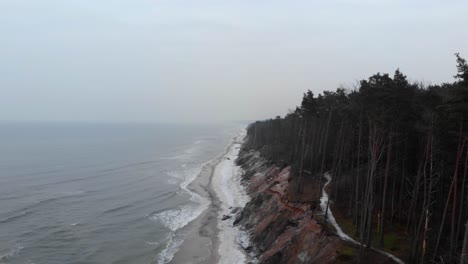 Aerial-shot-of-waves-crashing-into-sandy-beach-of-Ustka-in-winter