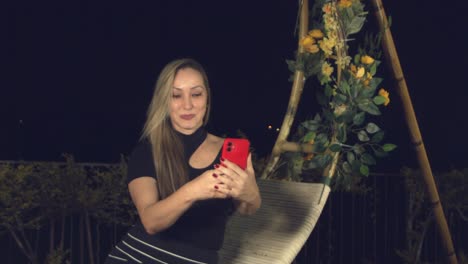 Mujer-Latina-Tomándose-Una-Selfie-Mientras-Posa-En-Un-Columpio-Afuera-Por-La-Noche