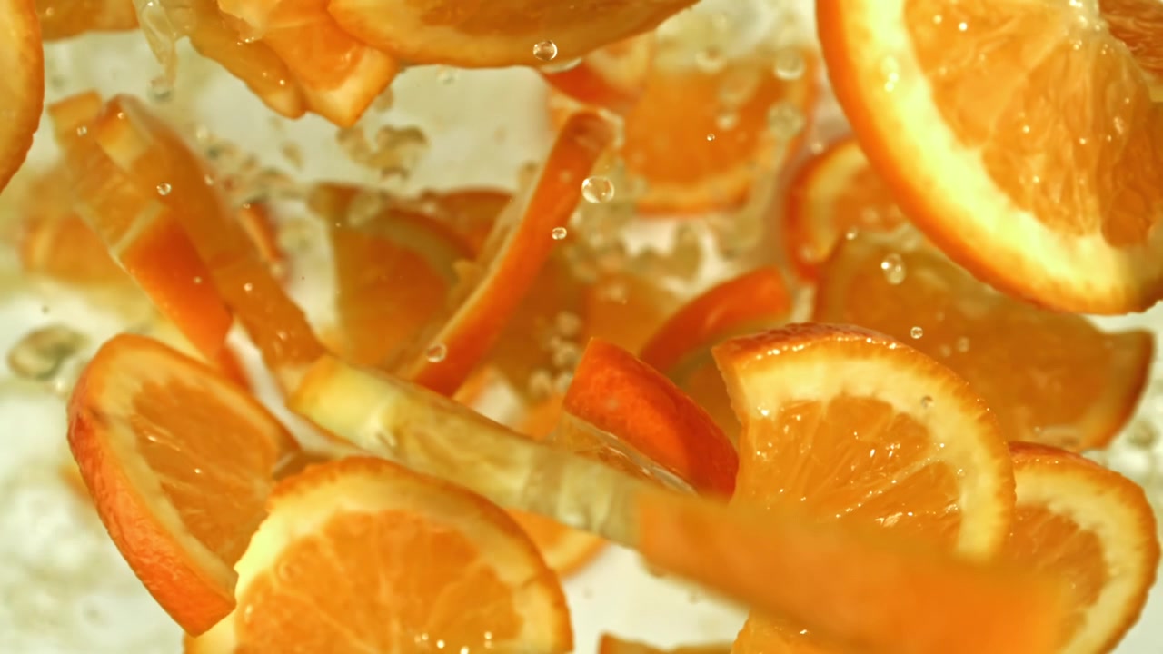 Fette di frutta arancione vivace che cadono in acqua limpida