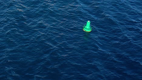 green buoy rocks in deep blue caribbean ocean water