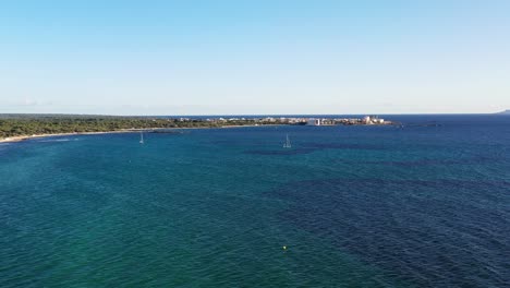 Playa-De-Estanys-En-La-Isla-De-Mallorca-España-Con-Veleros-Cerca-De-Los-Complejos-Hoteleros-De-Coto-Point,-Tiro-De-Aproximación-Aérea