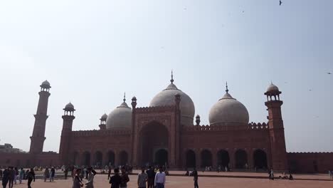 pan shot of badshahi mosque from the inside with people and flying birds in lahore pakistan