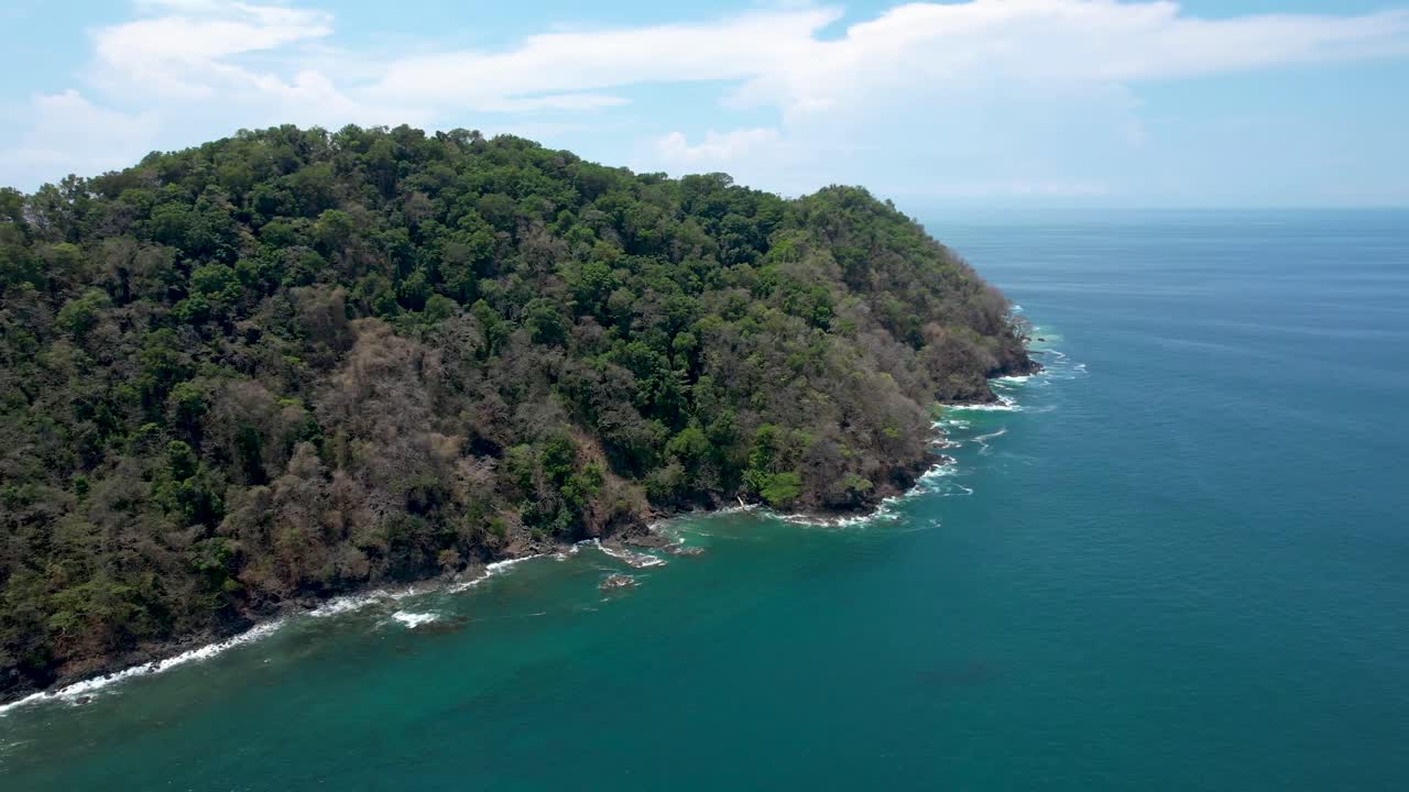 Herradura Island in Costa Rica, covered with lush green forest on sunny day -aerial