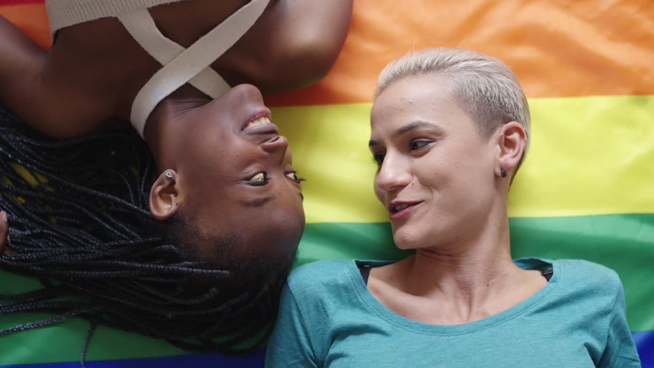 Two women lying on a pride flag