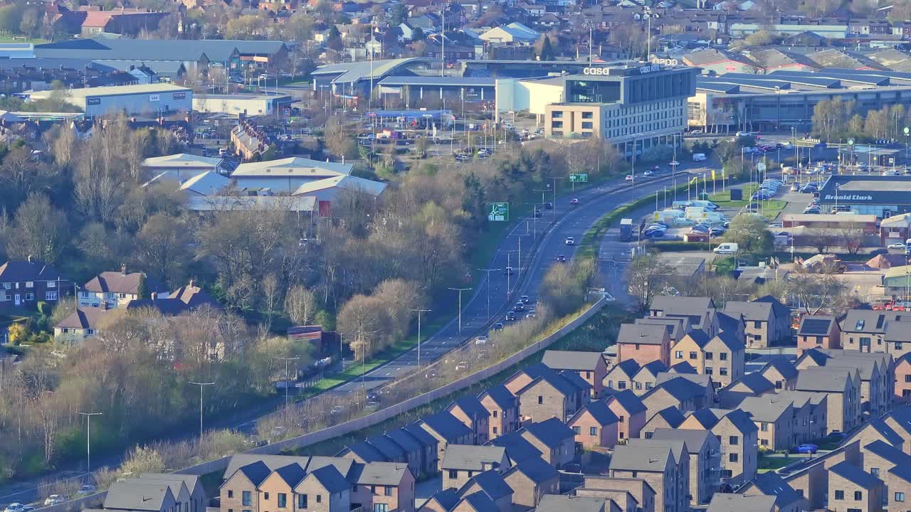 Aerial view of Chesterfield, Derbyshire, England. Golden light highlights residential homes, busy roads, and lush greenery, blending town charm with nature’s warmth.