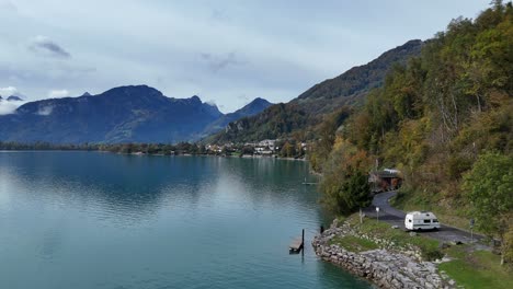 Stunning-aerial-drone-shot-of-Weesen---Switzerland,-on-a-bright-day-showing-a-calm-Walensee-lake-and-conifer-covered-mountains