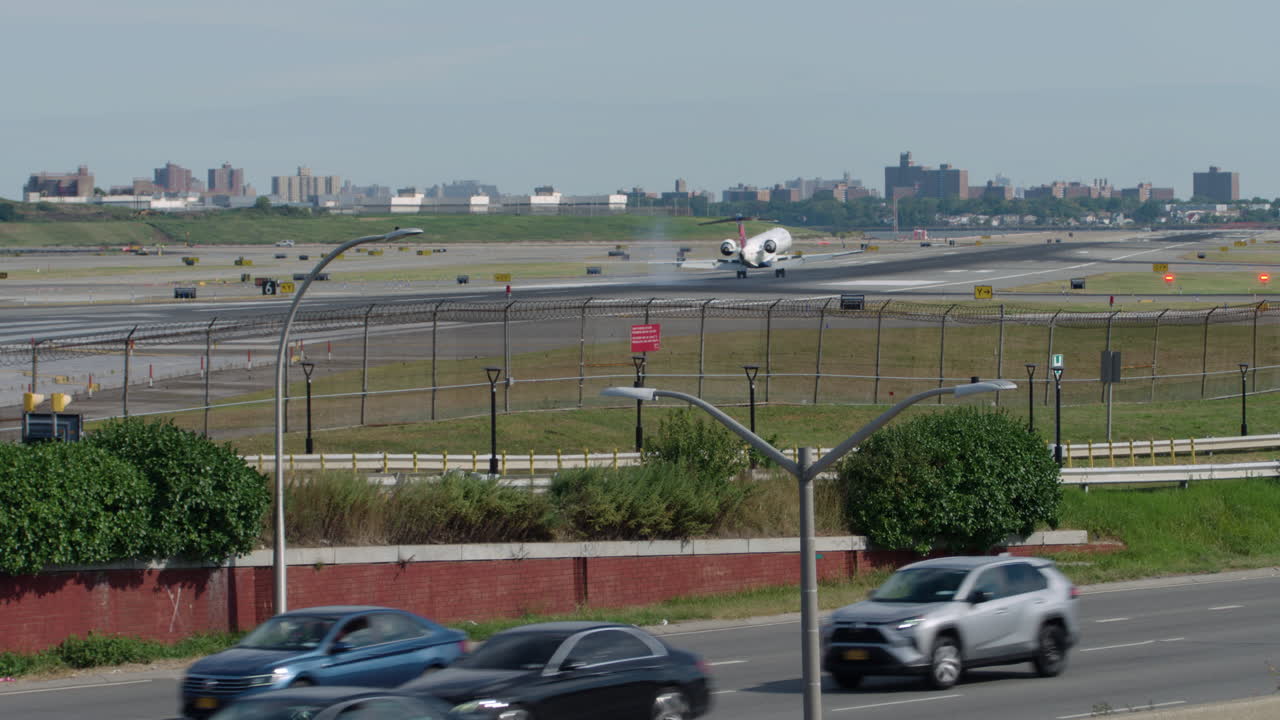 Cars Travel on Grand Central Parkway in Queens, New York, with Plane Landing on LaGuardia Airport Runway in Background