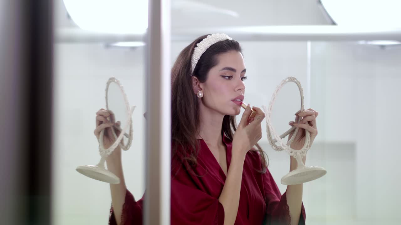 젊은 여성은 입술에 립스틱 제품을 부드럽게 미끄러뜨립니다.