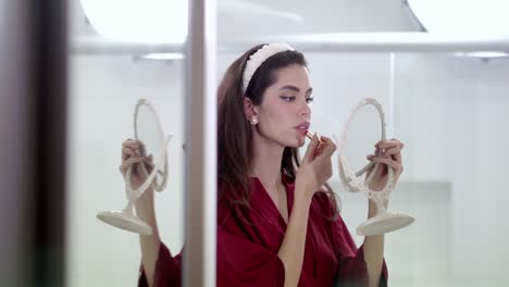 young woman delicately glides the lipstick product across her lips