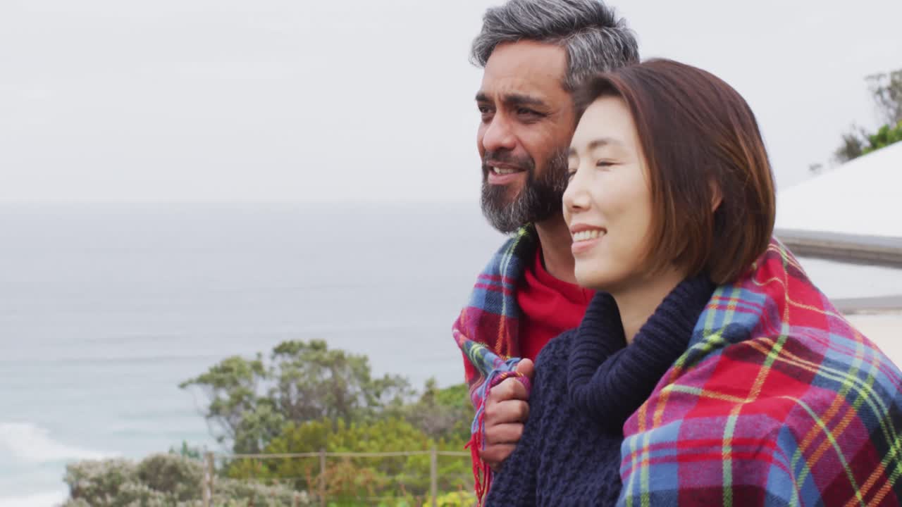 다양한 행복 한 부부는 담요 를 안고 발코니 에서 함께 이야기 하고 있다