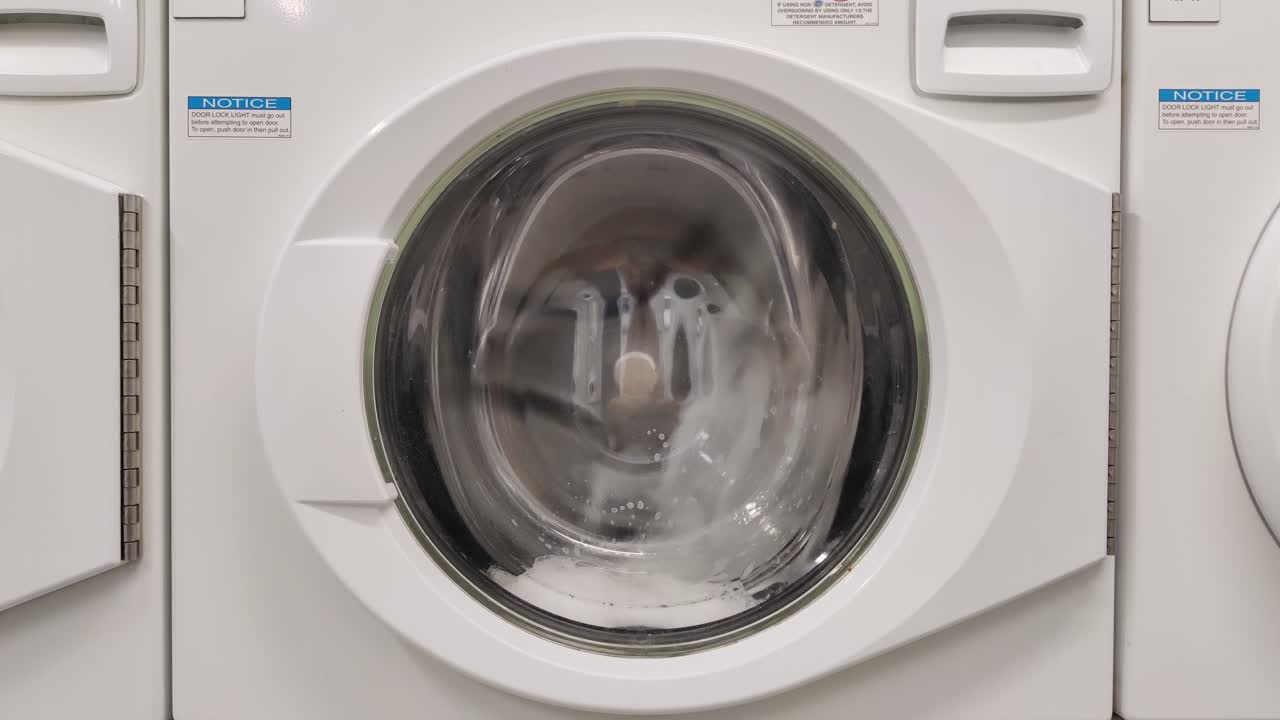 Close-up video of spinning drum washing machine | Washing clothing in domestic washing machine in home
