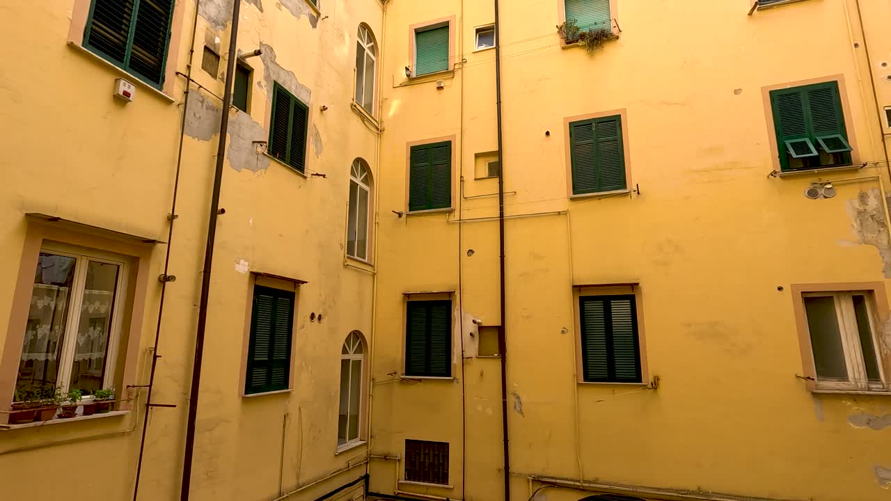 edificio amarillo con persianas y ventanas verdes