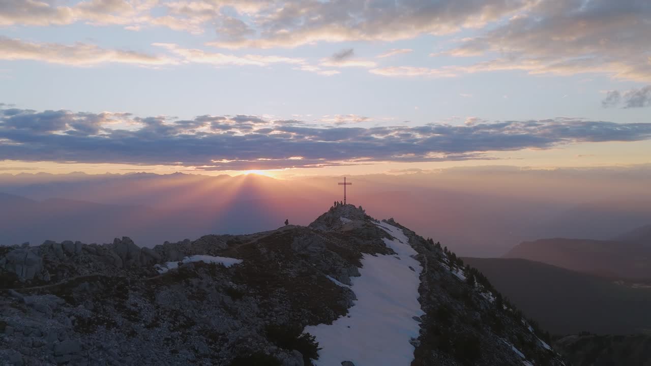 puesta de sol sobre corno bianco con una cruz en el pico de la montaña
