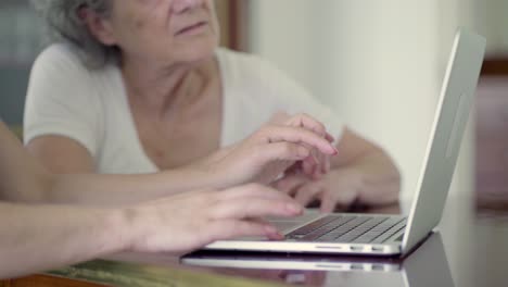 Zwei-Reife-Damen-Benutzen-Laptop,-Während-Sie-Am-Tisch-Sitzen.