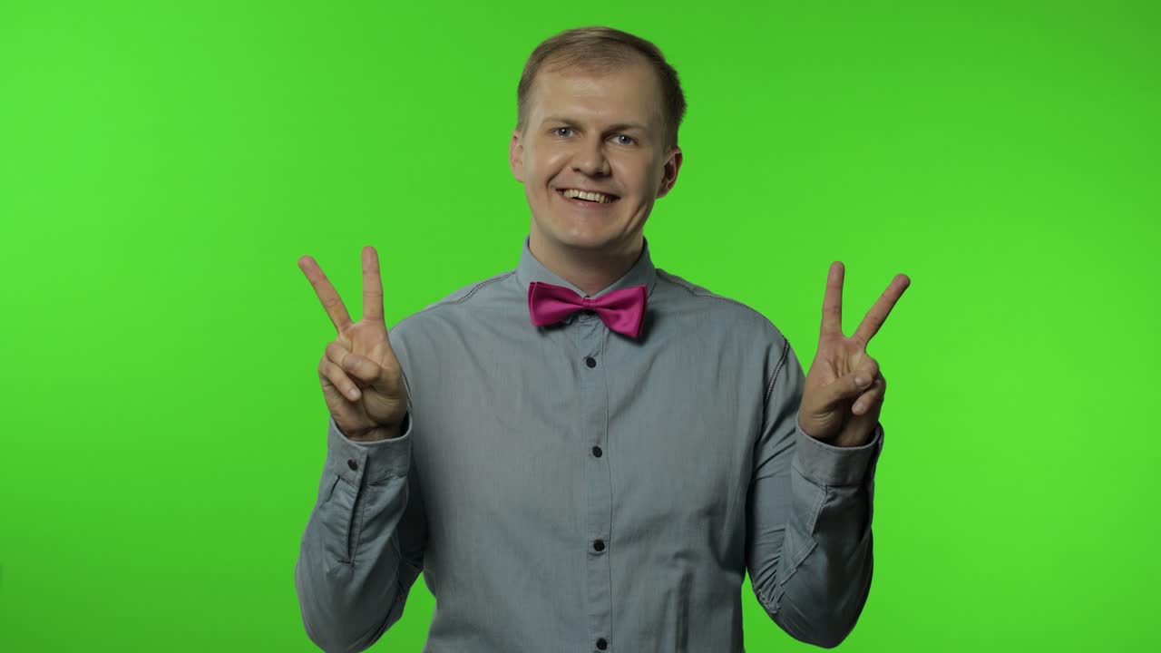 승리의 표시, 성공과 승리, 평화의 제스처와 친절하고 낙관적인 표정으로 미소 짓는 남자