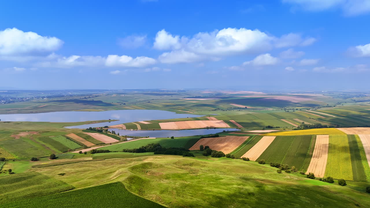 Fields and water scenery. Vast green fields and water body create a serene view under a bright blue sky with fluffy clouds