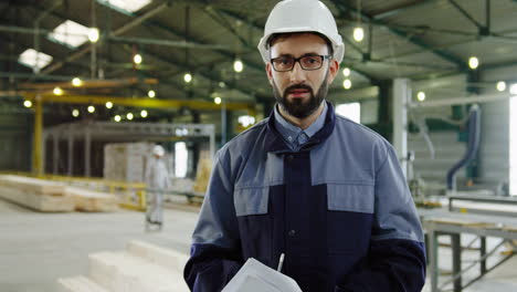 caucasian engineer wearing helmet and glasses in a big factory