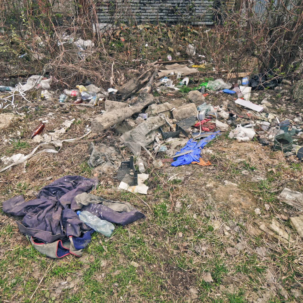 Different garbage lying on the ground in nature. A lot of plastic bottles, litter around the natural background. Pollution problem.