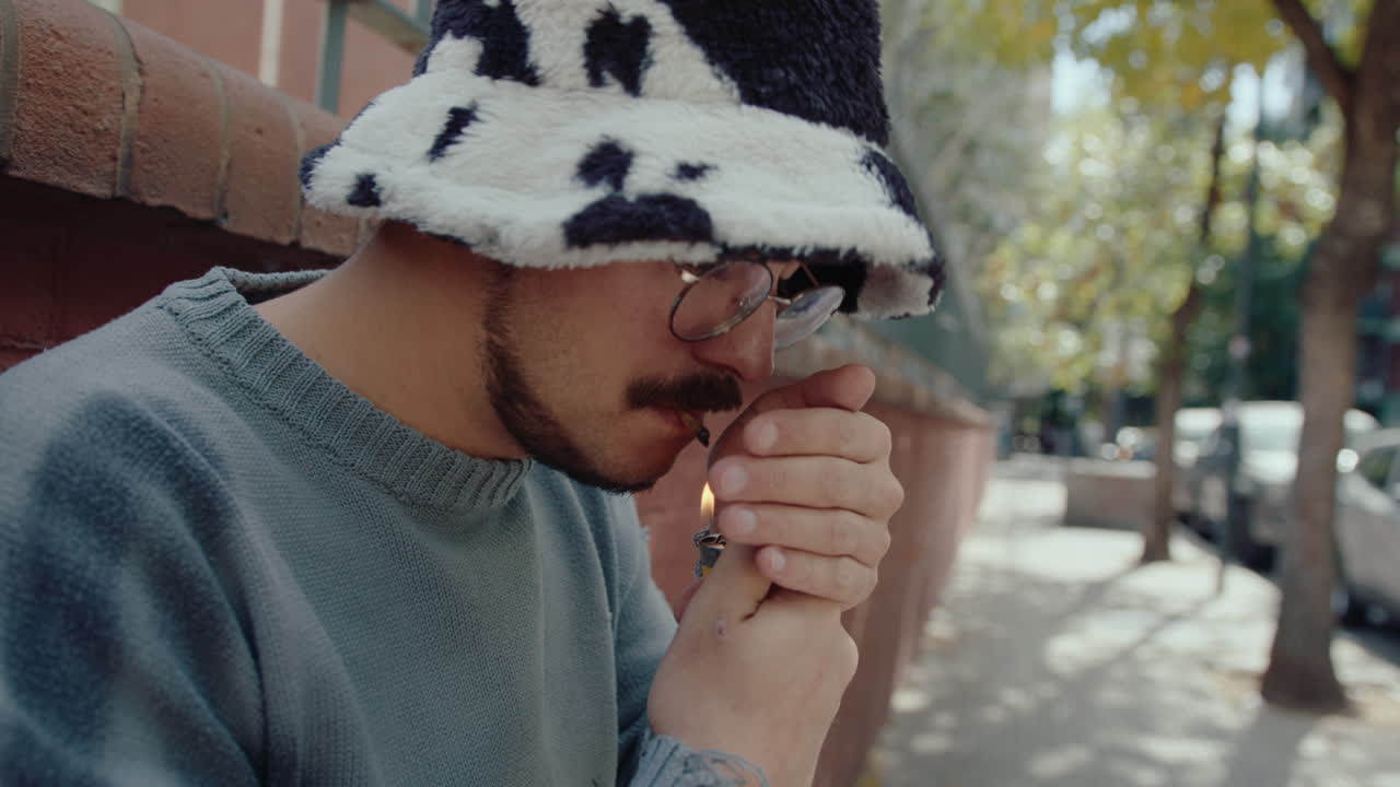 Young Man Smoking a Cigarette and Looking at Camera on the Street