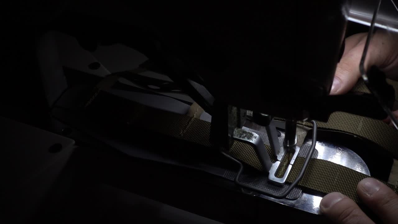 cámara lenta de un hombre que hace un traje militar en la máquina de coser muy compleja desde un lado