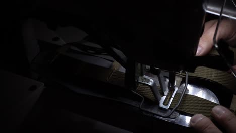 slowmotion of a man making a military costume on the very complex sewing machine from the side