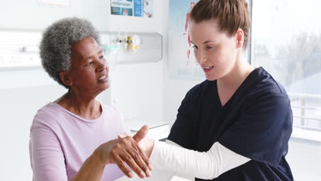 Mujer-Mayor-Diversa-Ejerciendo-La-Mano-Y-Doctora-Asesorando-En-El-Hospital,-Cámara-Lenta